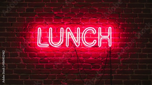 Bright red neon sign spelling lunch against a textured brick wall background