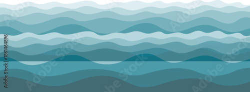 Calm sea waves in the foreground with misty mountains, hills, and a blue sky at sunrise creating a peaceful natural landscape