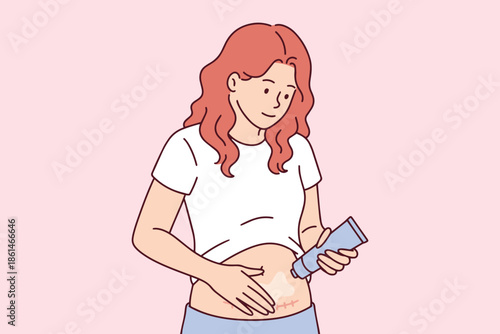 Young mother applying healing cream to C-section scar on belly. Woman cares for body after childbirth with medical ointment to reduce surgical incision marks on abdomen for postpartum recovery.