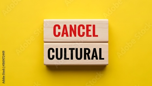 Wooden blocks spelling 'CANCEL CULTURAL' on a vibrant yellow background, representing the concept of cancel culture and societal discourse.