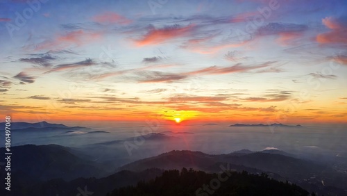 Vibrant sunrise above misty mountain peaks with a radiant sky