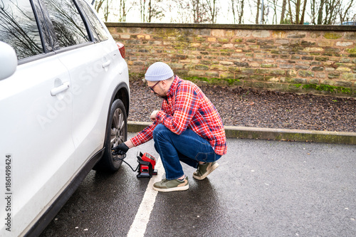 Quadro su tela Man using portable air pump inflate a car tire