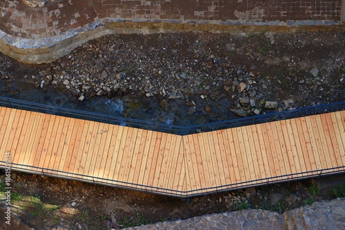 A pedestrian wooden bridge along a mountain stream between steep cliffs, view from above