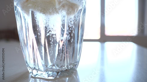 Pouring powdered supplement into a glass filled with water and than mixing the powdered supplement with a spoon