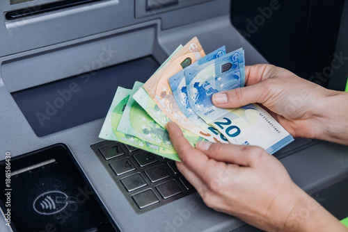 Billede på lærred Hands holding various euro banknotes while using an ATM, showcasing the process