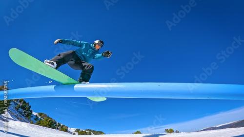 Billede på lærred LOW ANGLE VIEW: Snowboarder doing a stylish boardslide trick on a blue rail