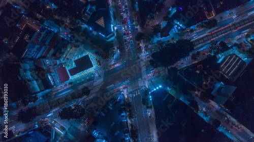 Top down hyperlapse over a busy intersection in Mexico City at night, as the drone ascends to reveal traffic flow, light trails, and the urban grid illuminated by city lights.