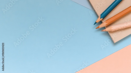 Minimalist Composition with Three Pencils on Textured Paper in Pastel Blue Peach and Beige Colors and Soft Shadow Top View