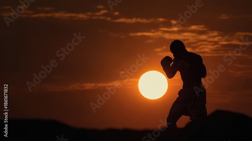 Silhouette of a Boxer in a Fighting Stance Against a Fiery Sunset with Dramatic Clouds.