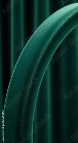 Closeup of a curved plush emerald velvet fabric against a soft dark green pleated background
