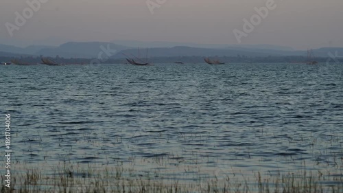Boat sailing on calm water under a blue sky with clouds during a peaceful winter evening day, Ubonratchathani Thailand