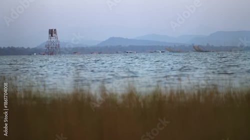Boat sailing on calm water under a blue sky with clouds during a peaceful winter evening day, Ubonratchathani Thailand