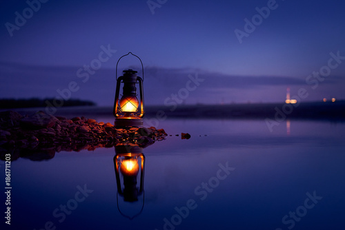 Burning old lantern on rocks reflecting in the river