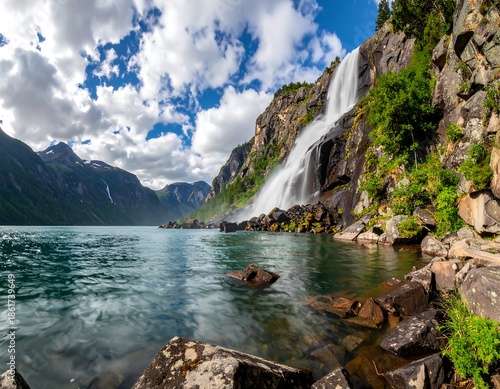 Scenic waterfall cascading into a serene lake, framed by mountains