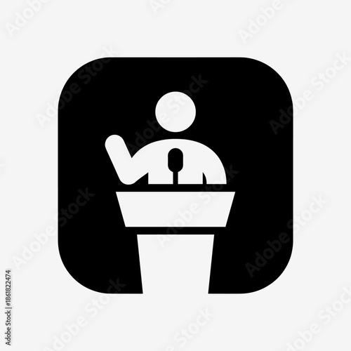 A black and white icon depicting a speaker at a podium with a microphone, gesturing with one hand.