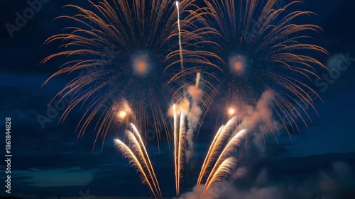 Vibrant fireworks exploding in dark night sky with orange sparks