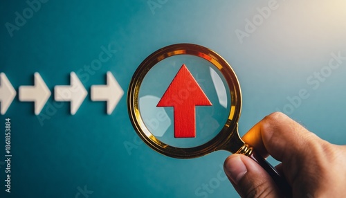 Magnifying glass focuses on red arrow pointing upwards symbolizing growth and success