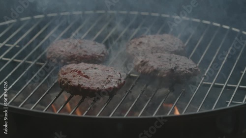 Flaming hot griller with burger yummy juicy burger patties being flipped over