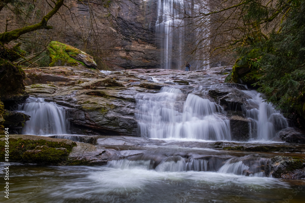 Fototapeta premium A serene view of Suuçtu Waterfall in Bursa, with water cascading over moss-covered rocks, surrounded by lush greenery and trees, creating a peaceful, natural landscape perfect for nature lovers.