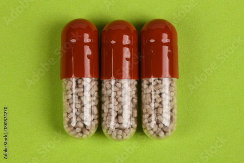 Three Pharmaceutical Capsules on Green Background Healthcare Concept