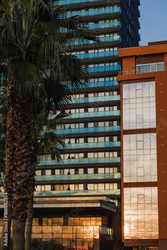 Modern hotel facade with glass balconies and sunset reflections in Batumi