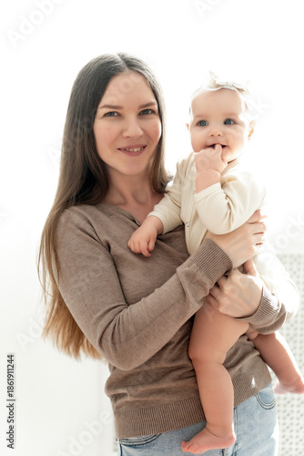 mom and baby hug and kiss on a white background of the window, a place and space for text, maternal love and care, mother and child in their arms