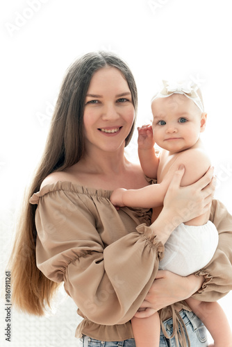 mom and baby hug and kiss on a white background of the window, a place and space for text, maternal love and care, mother and child in their arms in diapers