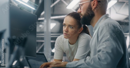 Engineers Reviewing Network Performance Data. Male and Female IT Engineer Team Collaborating Over Computer Monitor to Review Critical Network Performance Metrics. Teamwork and Real Time IT Monitoring.