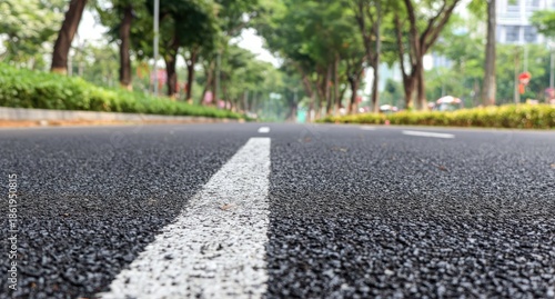 Asphalt road with white line, trees, and cityscapes in the background