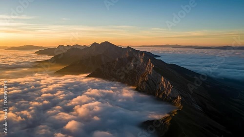 Majestic mountain range emerges from sea of clouds at sunrise.