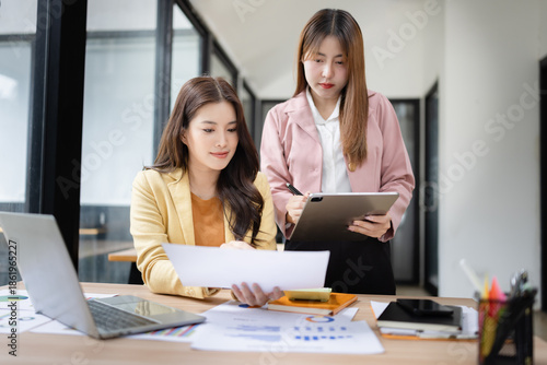 Wallpaper Mural Two asian businesswoman using digital laptop and talking about business with analyzing financial charts in the modern office. Torontodigital.ca