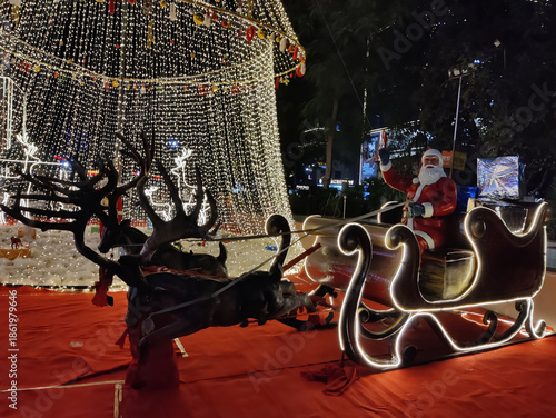 Jaipur, India 24 December 2025: Picture of Christmas decoration in a mall in Jaipur on Christmas eve shot against dark background. Santa Claus rides on a reindeer
