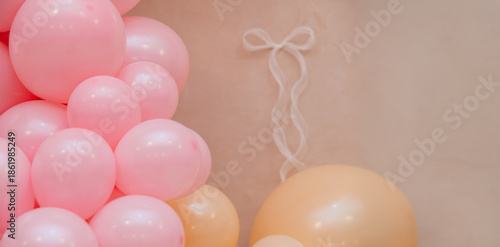 Soft pastel balloon decoration with pink and peach balloons on beige background. Delicate festive scene with copy space, suitable for baby shower, birthday or gentle celebration design.