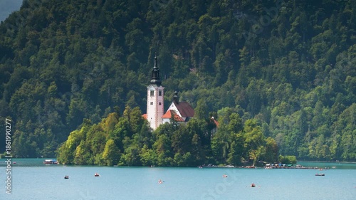Bled, Slovenia - August 11, 2025: The iconic Assumption of Mary Church sits on a lush, forested island in the middle of the turquoise Lake Bled, surrounded by steep Alpine mountains.