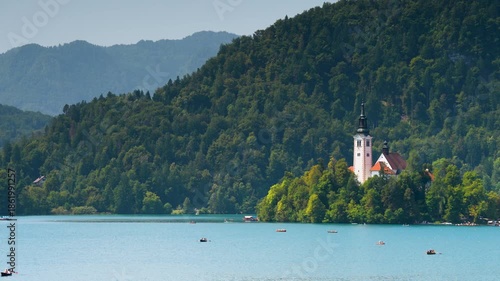 Bled, Slovenia - August 11, 2025: The iconic Assumption of Mary Church stands on a forested island amidst the turquoise waters of Lake Bled, framed by majestic Alpine mountains