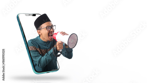 Asian Muslim man in green outfit shouting through megaphone, emerging from smartphone screen. Concept of digital announcement and online communication. Isolated on white background.