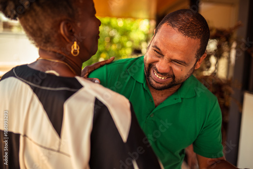 Fotografie Joyful Black man laughing heartily with an older woman, sharing a happy moment together outdoors