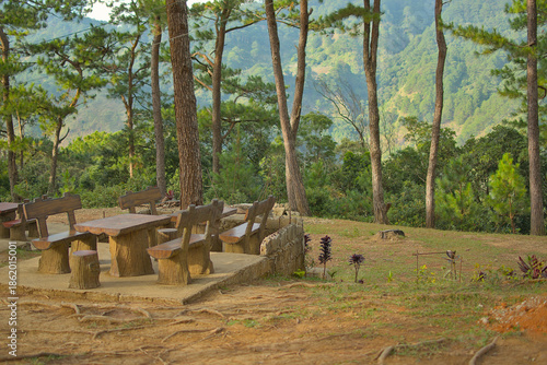 A serene park perched atop a mountain, featuring rustic wooden tables and benches.