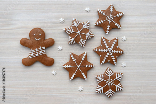 Romantic decorated gingerbread cookies in a shape of star and man with notes on a staff, small snowflakes around