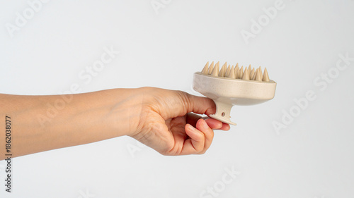 A hair comb used for massaging the scalp while washing hair, held in the hand against a white background.