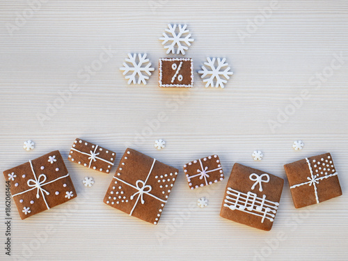 Decorated gingerbread cookies - christmas presents and a percent sign with snowflakes on a light background, copy space for text. Christmas or winter discount and sale concept