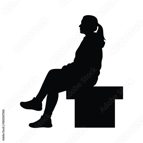 Silhouette of a young girl sitting on a cube against a plain white background.
