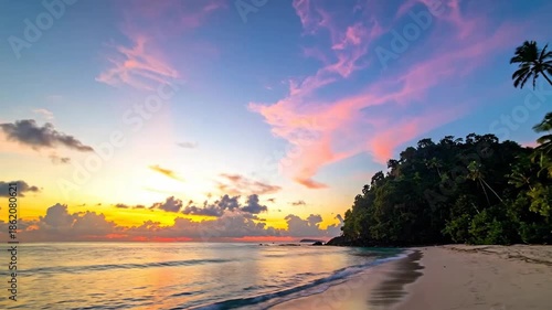 Tropical beach paradise at sunset with pink clouds and palm trees.