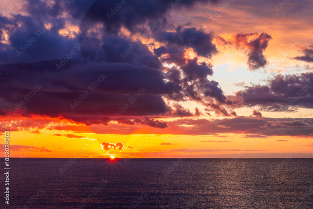 Obraz premium Dramatic seascape of sunset or sunrise sky with clouds during morning or evening. Dramatic sunset over the sea with orange clouds and sun above ocean water