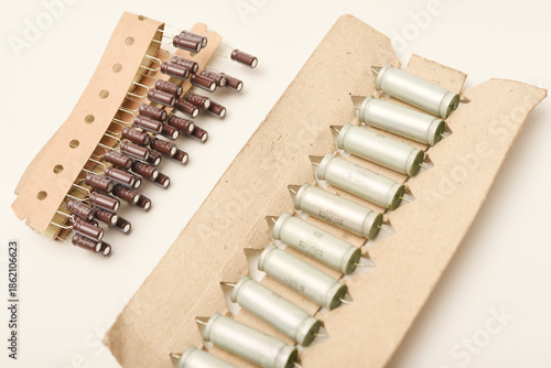 Old capacitors in paper tape. Aluminum capacitors on a white background. The electronic components are in their original packaging.