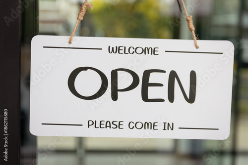 Open sign on door in front of restaurant, coffee shop or store. Open sign board hanging on glass door at entrance coffee cafe shop or restaurant.