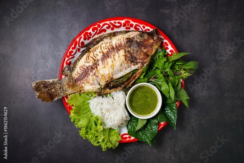 Thai grilled salt crusted fish (Miang Pla Pao) served with rice vermicelli and vegetables on a traditional tray.