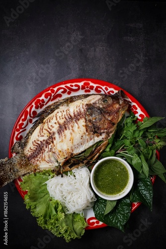 Thai grilled salt crusted fish (Miang Pla Pao) served with rice vermicelli and vegetables on a traditional tray.