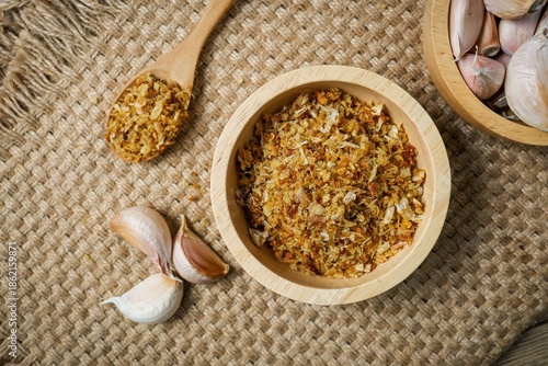 Crispy fried garlic in a wooden bowl on a rustic sackcloth background.