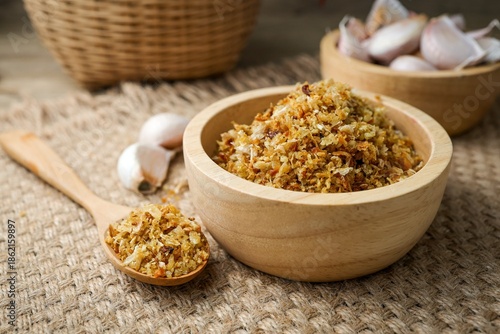 Crispy fried garlic in a wooden bowl on a rustic sackcloth background.
